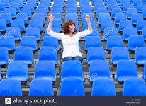 lone-female-fan-or-spectator-sitting-cheering-in-amongst-rows-of-empty-GHDAD1.jpg
