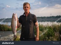 stock-photo-a-man-with-a-fish-caught-in-the-hands-of-a-lake-wild-pride-777940624.jpg